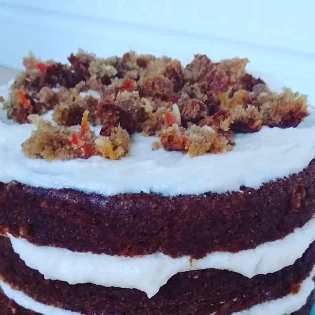Naked carrot layer cake with cream cheese frosting and crumbled cake on top
